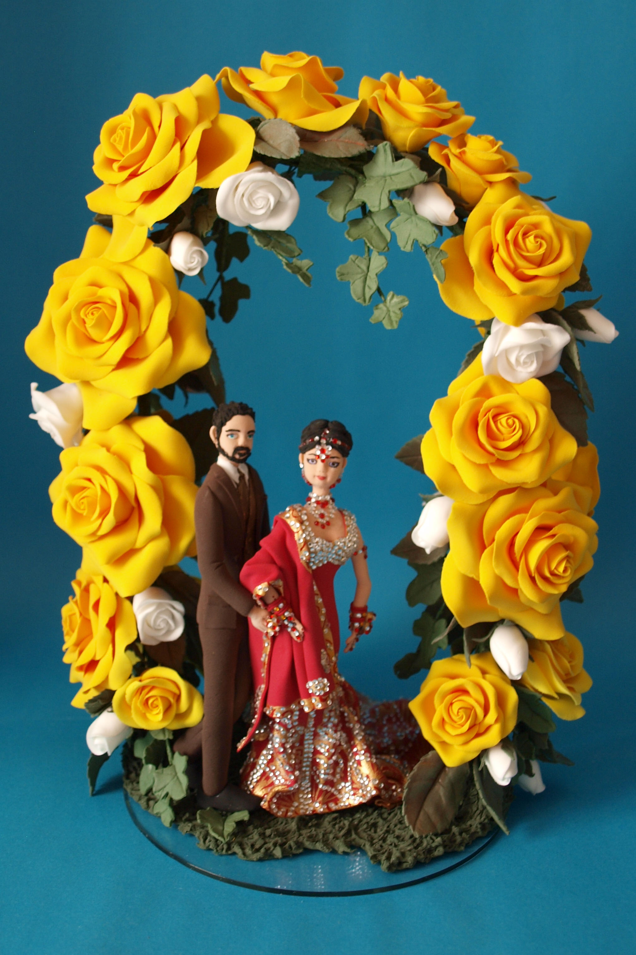 Asian bride and groom with large rose flower arch wedding cake topper by Louisa Hill